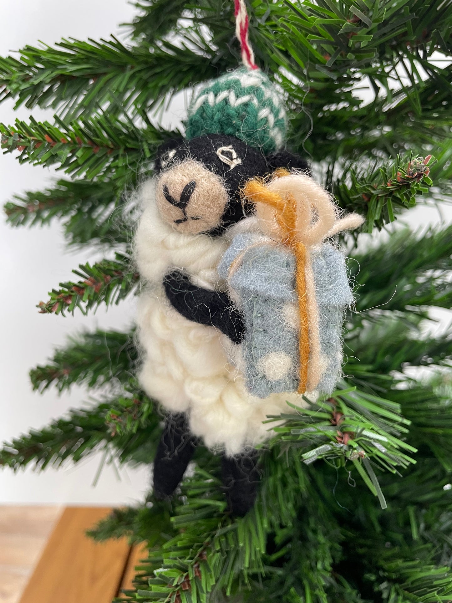 100% wool felt Christmas Ornament of a cute little Black Sheep holding a gift.