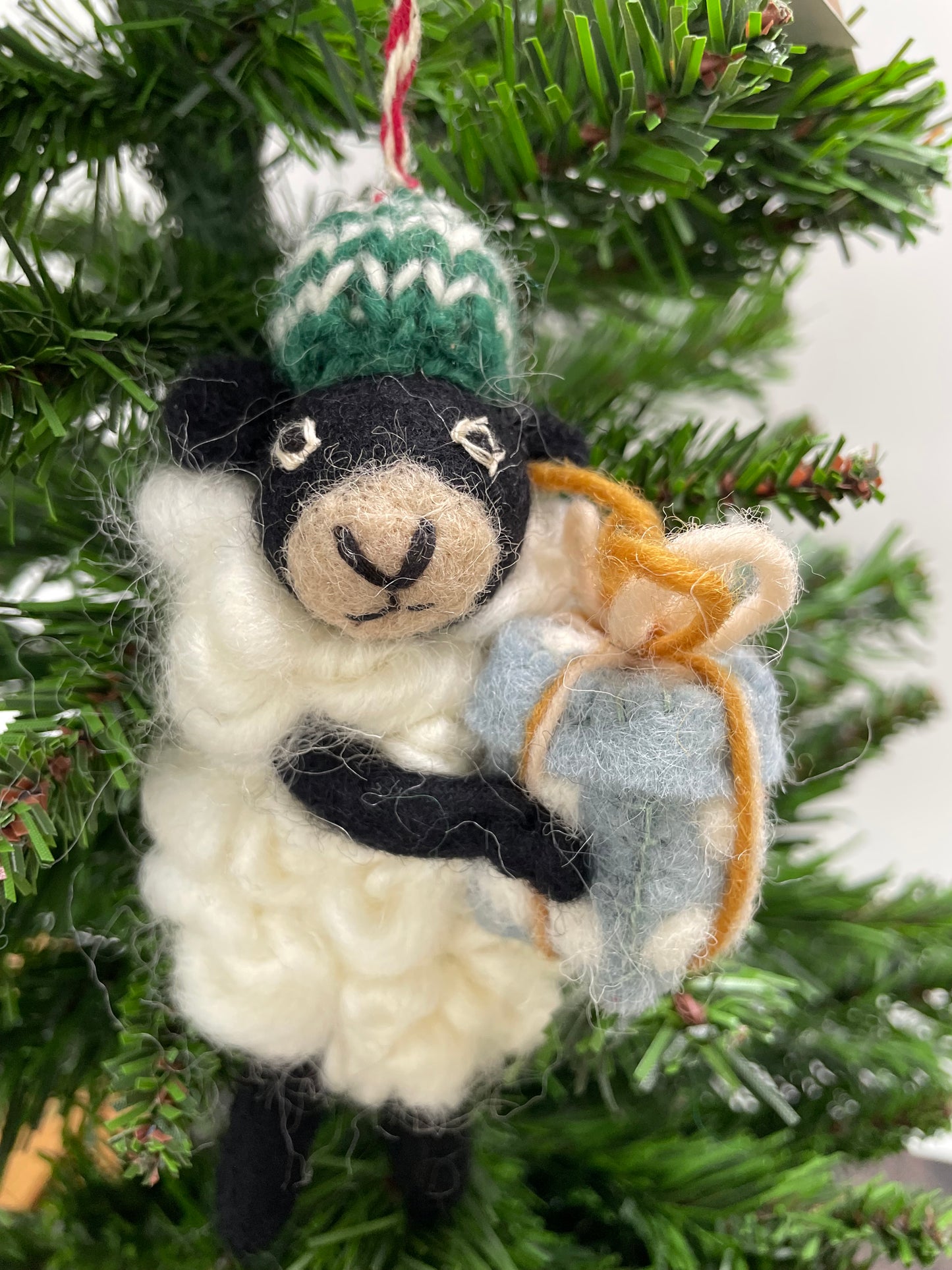 100% wool felt Christmas Ornament of a cute little Black Sheep holding a gift.