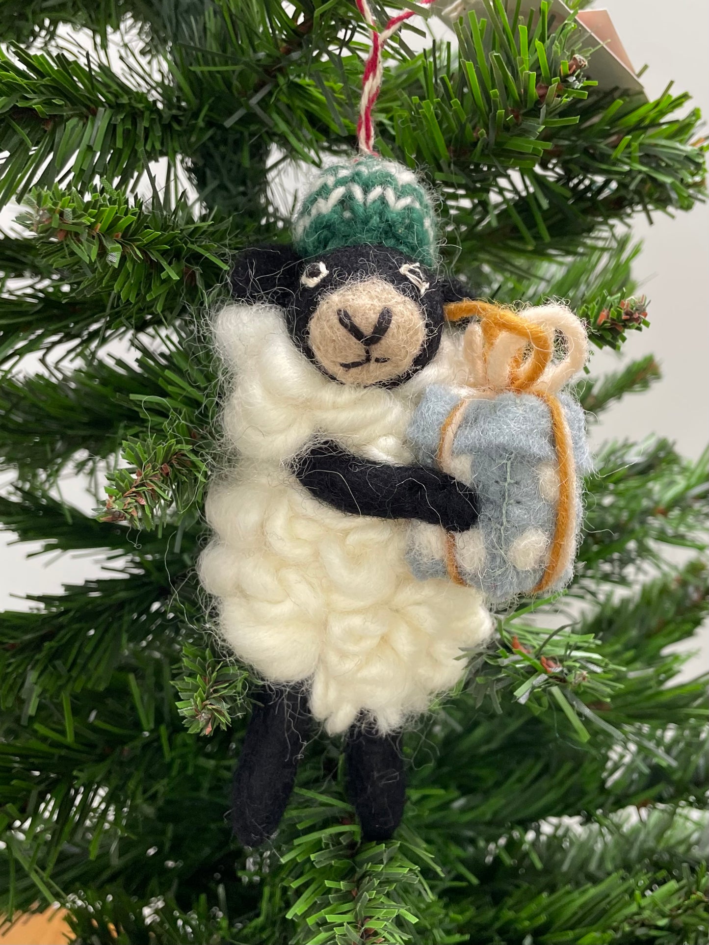 100% wool felt Christmas Ornament of a cute little Black Sheep holding a gift.