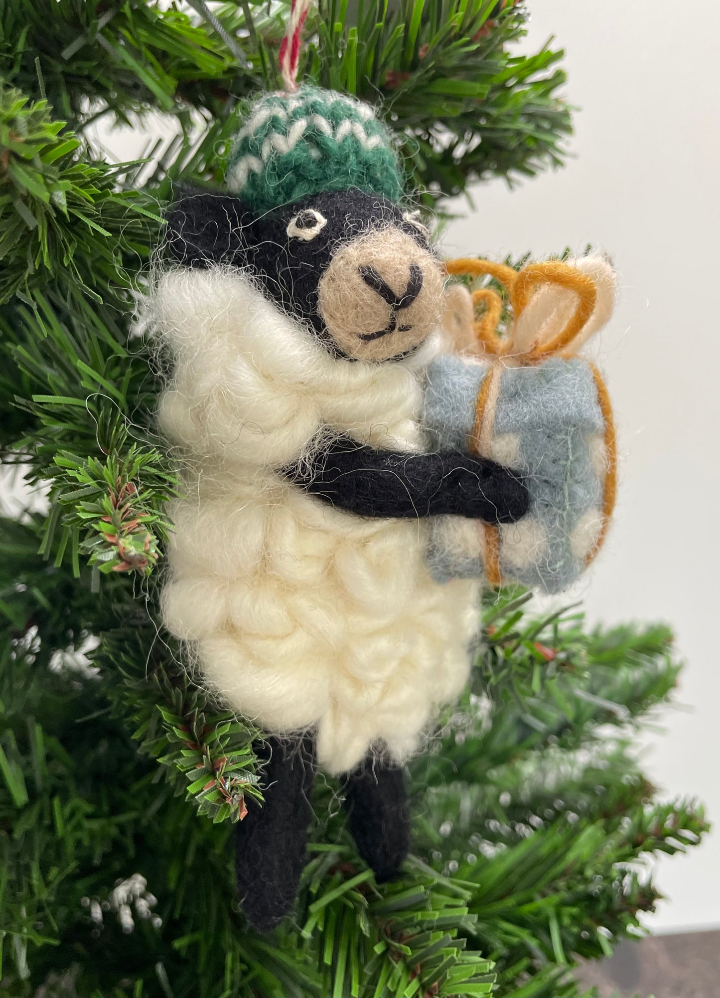 100% wool felt Christmas Ornament of a cute little Black Sheep holding a gift.