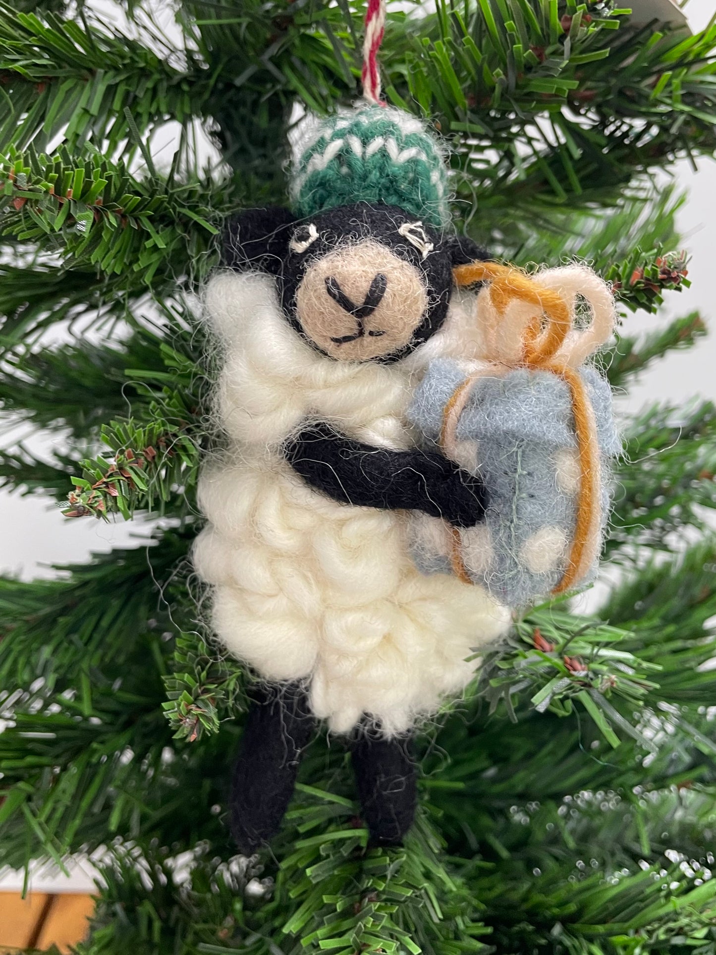 100% wool felt Christmas Ornament of a cute little Black Sheep holding a gift.